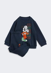 Zilas pelēkais krekls un bikses, kas izgatavotas no mīksta auduma, ar grafiku, kurā attēlots Mikijs Rūks oranžā un zaļā krāsā, blakus tam uzdrukāts "Adidas".