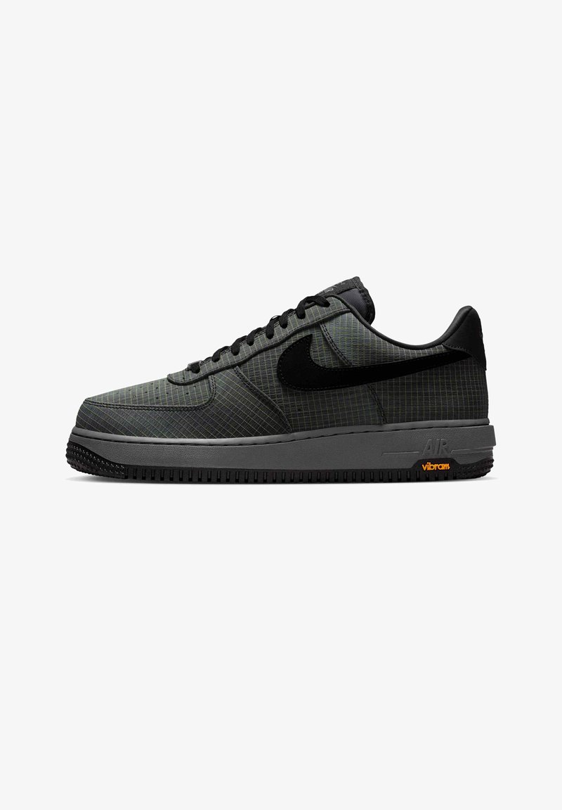 Niski sneaker Nike Air Force 1 w ciemnoszarym kolorze z czarnym logo, cholewką w kratkę, czarnymi sznurowadłami oraz podeszwą sygnowaną marką Vibram.