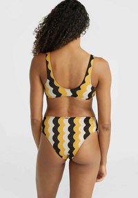 Dvodijelni bikini set s valovitim uzorkom u žutoj, crnoj i bijeloj boji. Materijal je rastezljiv, s donjim dijelom srednjeg struka i širokim trakama.