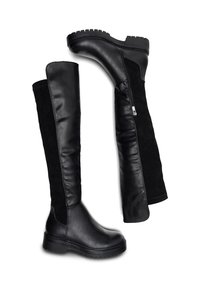 Botas negras hasta la rodilla con suelas gruesas, paneles frontales de cuero suave, paneles traseros de ante y cremalleras laterales sobre un fondo blanco.