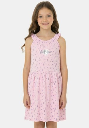 Jeune fille souriante, portant une robe rose sans manches avec de petits motifs de feuilles violettes et un logo "Lee Cooper" sur la poitrine.
