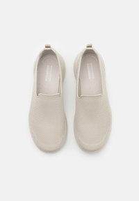 Chaussures beige à enfiler avec une tige en mesh et une surface texturée. Présente un design minimaliste avec une boucle au talon pour un enfilage facile.