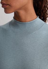 Lichtblauw, aansluitend topje met een hoge halslijn, gemaakt van een glad, zacht materiaal, met een naadloos ontwerp en subtiele textuur.