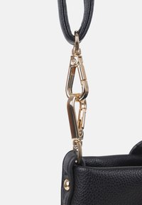 Schwarzer strukturierter Leder-Taschenecke mit goldfarbenen Metallverschlüssen und Ringen, die einen schwarzen Riemen befestigen.