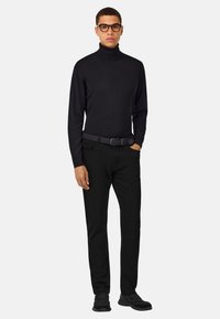 Černý rolák a černé kalhoty, doplněné černým pásem a černými botami. Modelka má krátké vlasy a brýle. Jednoduchý, přiléhavý design.