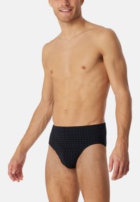 Slips de bain navy avec un motif en grille, fabriqués à partir d'un tissu lisse, présentant un design ajusté et une ceinture confortable.