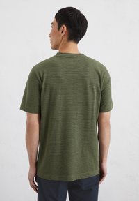 Olive green short-sleeve t-shirt with horizontal stripes, round neckline, and a relaxed fit, shown from the back against a light background.