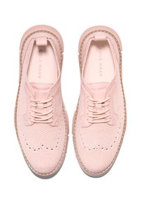 Light pink knit shoes with a textured surface, rounded toe, and traditional lacing. Synthetic upper with contrasting stitching and rubber sole.