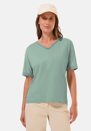 Mintgroene T-shirt met korte mouwen en een V-halslijn met decoratieve stiksels, gemaakt van zacht materiaal, gecombineerd met lichtbeige broeken.