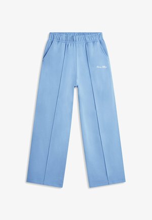 Pantalon large bleu clair avec ceinture élastique, poches latérales, plis sur le devant, et petit logo blanc « Tommy Hilfiger » sur la cuisse droite.