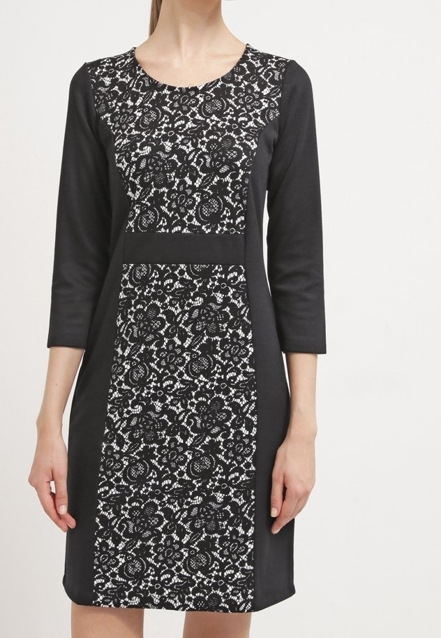 Svartvit klänning med rund halsringning, trekvartslånga ärmar, med spetsmönster i mitten och solida svarta sidor.
