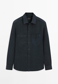 Knappt skjorta i mörkblå denim. Har spetsig krage, två framfickor och långt ärmar med knäppning vid handlederna.