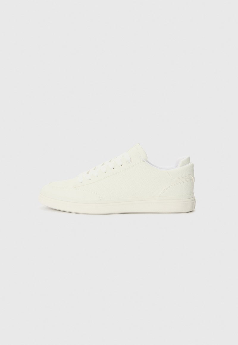 White sneakers featuring a smooth textured upper, round toe, and traditional lacing, with a minimalistic design and rubber sole.