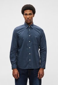 Μπλε καρώ πουκάμισο από βαμβ�άκι, με κλασικό γιακά, κουμπώματα μπροστά και τσέπη στο στήθος. Μακριά μανίκια με κουμπιά στους καρπούς.