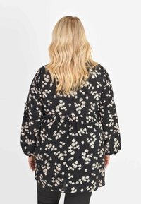 Blusa nera a fiori con maniche lunghe, caratterizzata da un motivo floreale dai toni chiari e un dettaglio in vita arricciato. Tessuto morbido e leggero.