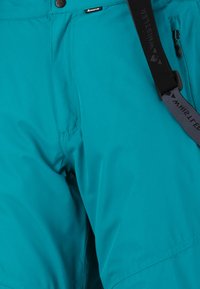 Teal outdoor broek van een gladde, lichte stof. Voorzien van verstelbare banden, een ritszak en versterkte stikdetails.