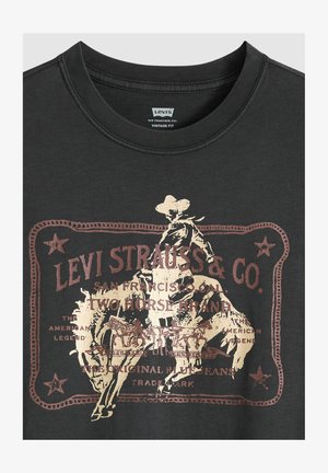 T-shirt in cotone nero con grafica in stile vintage color bronzo, raffigurante un cowboy a cavallo con testo dettagliato e bordi.