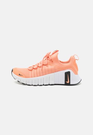 Nike running shoe in vibrant peach color with a breathable mesh upper, textured design, and a white, ridged sole. Features black logo accents.