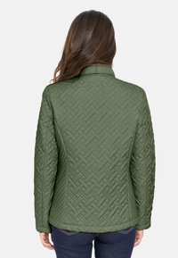 Chaqueta acolchada verde olivo con textura tejida, cuello mao y mangas largas. Presenta un corte recto con un ajuste entallado.