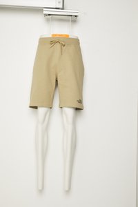 Pantaloni corti beige in cotone con cordoncino, all'altezza del ginocchio, caratterizzati da un piccolo logo nero sul lato sinistro, mostrati su una manichino bianco.