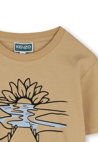 Beige katoenen T-shirt met een zwarte grafische print van een zon en rivier met blauwe accenten, ronde halslijn en korte mouwen.
