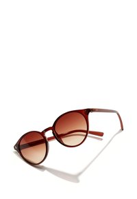 Burgundy aurinkolasit, joissa on ylisuuria, pyöreitä linssejä ja lämpimänruskea gradienttiväri. Läpikuultava muovikehys, jossa on kapeat templet ja logotieto.