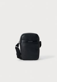 bolsa crossbody de pele preta com formato retangular, superfície texturizada, fecho com zíper, alça ajustável e logotipo da marca em relevo.
