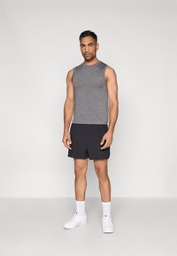 Γκρι αμάνικη μπλούζα, μαύρο σορτς, λευκά αθλητικά παπούτσια και κάλτσες τύπου crew. Απλός σχεδιασμός, ελαφρύ ύφασμα, άνετη εφαρμογή, κατάλληλο για αθλητική ένδυση.