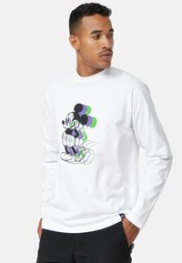 Maglietta bianca a maniche lunghe con una grafica di Topolino con palloncini in viola e verde. Tessuto di cotone morbido con una vestibilità comoda.