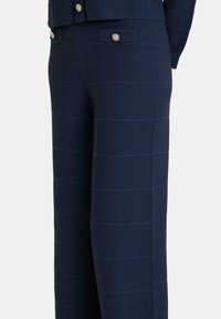 Pantalons larges bleu marine en tissu tricoté texturé, dotés de rayures horizontales, d'une taille haute et de boutons décoratifs sur les poches avant.