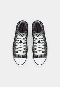 Tenisi high-top în imprimeu de leopard negru și gri, având șireturi albe, vârf de cauciuc și un exterior din țesătură texturată.