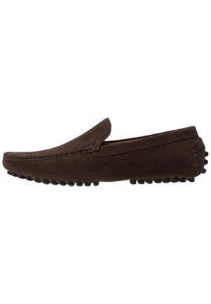 Brauner Herren-Slipper aus Wildleder mit abgerundeter Spitze, genähten Details und Gummisohlen mit Noppen, von der Seite vor weißem Hintergrund gezeigt.