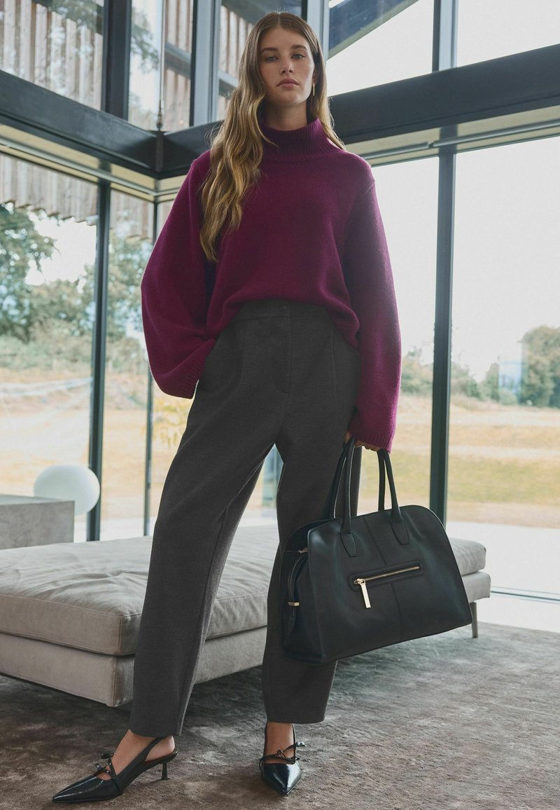 Bordo turtleneck pulover, sivi hlače s visokim strukom, crna kožna torbica s patentnim zatvaračem i cipele na posrednjoj potpetici s mašnom.
