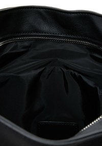 Interior de bolsa de cuero negro con una textura suave, que cuenta con un cierre de cremallera y un forro de tela en tonos oscuros, creando un diseño elegante y funcional.