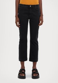 Black cropped jeans with a fitted design, featuring a classic five-pocket style and rolled cuffs, made from a smooth denim material.