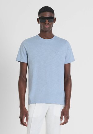 T-shirt azzurro chiaro a maniche corte con scollatura rotonda e una leggera texture. Presenta un dettaglio del logo in rilievo sul lato sinistro del petto.