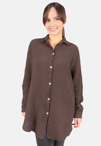 Brown button-up shirt made of textured fabric, featuring a collar, long sleeves, and a relaxed fit with front buttons and side slits.