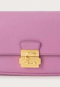 Borsa a tracolla in pelle rosa con superficie strutturata, dotata di una chiusura dorata con un logo doppia C. Forma rettangolare compatta con chiusura a patta.