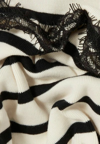 Tela de punto con un patrón de rayas beige y negras, que presenta un delicado borde de encaje negro a lo largo de un borde, mostrando textura y contraste.