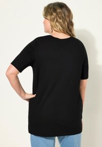 Svart kortärmad t-shirt med avslappnad passform och rund halsringning, i ett slätt tyg och med mellanhöjd, kombinerad med ljusblå jeans.