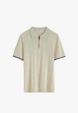 Polo beige à manches courtes avec un col zippé, présentant une texture côtelée verticale et des accents bleu marine sur les ourlets des manches.