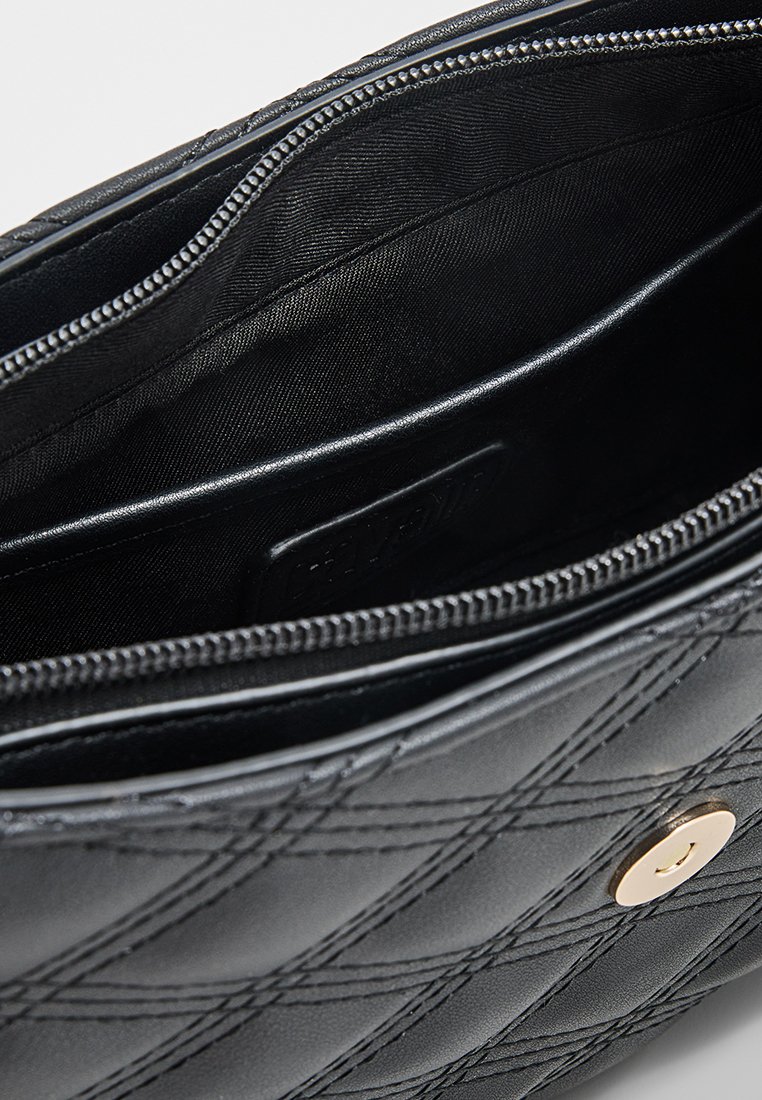 Interno di una borsa in pelle nera con chiusura a zip, molteplici scomparti e una texture liscia con un sottile motivo trapuntato.