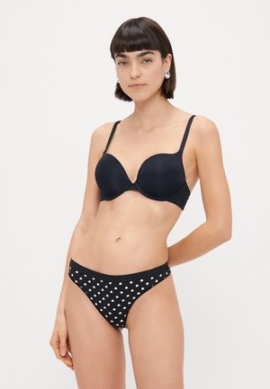 Soutien-gorge noir rembourré avec des sangles réglables, associé à un bas de bikini noir avec un motif à pois blancs. Tissu lisse et design simple.