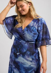 Blå blommig klänning med korta, genomskinliga ärmar, med en v-ringning och delikat svart kant. Mjuk material med en slät textur.