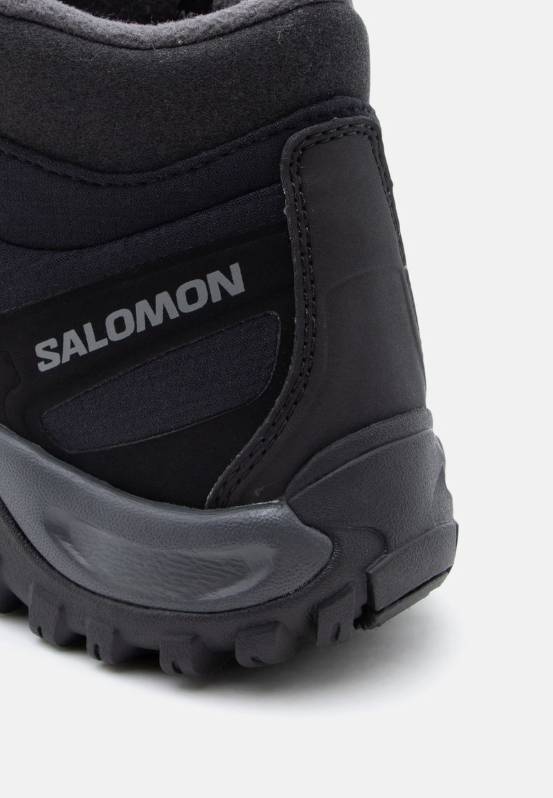 Sort vandrestøvle med en tekstureret syntetisk overdel, forstærket hæl, polstret krave og en robust gummisål med dybe dækmønstre for godt greb.