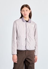 Ελαφρύ μονωμένο μπουφάν σε γκρι ανοιχτό χρώμα, με κλείσιμο μπροστά με κουμπιά και κοντράστ γιακά. Ομαλό ύφασμα με ελάχιστες ραφές.