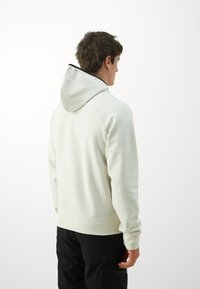 Hellgrauer Kapuzenpullover mit gerippten Bündchen und Saum. Der Rücken zeigt ein sauberes, minimalistisches Design.