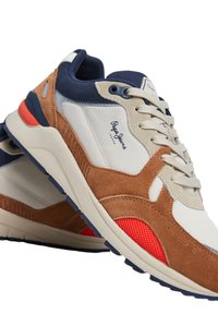 Zapatillas multicolor que combinan materiales de ante y malla; los colores incluyen marrón, azul marino, crema y rojo con acentos texturizados y logotipo.