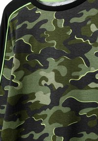 Mikina so vzorom camouflage v rôznych odtieňoch zelenej a čiernej, s čiernym výstrihom a žiarivo zeleným lemovaním pozdĺž švov.