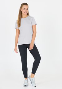 Ljusgrå atletisk t-shirt, kort ärm, mjukt material. Tillsammans med svarta leggings och grå löparskor. Enkel, modern design.